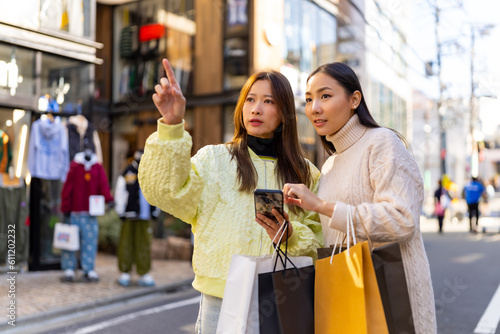 Canvas Print Asian woman friends using navigator app on mobile phone during shopping together at Shibuya district, Tokyo, Japan