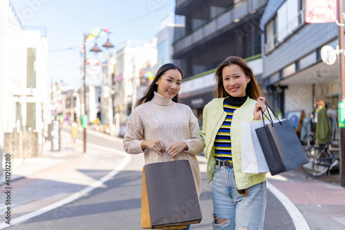 Happy Asian woman friends walking and shopping together at Shibuya district, Tokyo, Japan in autumn. Attractive girl enjoy and fun outdoor lifestyle walking and travel city street on holiday vacation.