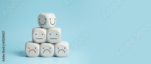 world mental health day concept or feedback rating and positive customer review, wood cube stacking with emotion face icon on blue background