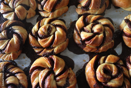 Hot Kanelbullar, traditional swedish cinnamon and cardamon buns on the baking pan photo