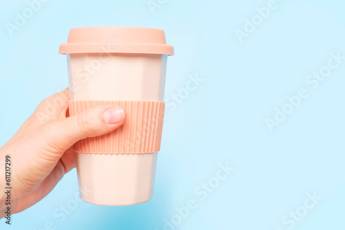 Fotografie Female hand hold ceramic glass with coffee on blue background, side view