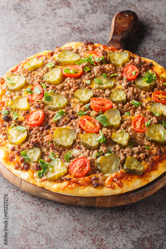 Homemade Fatty Hamburger Pizza with Beef Pickles and Tomato closeup on the wooden board on the table. Vertical
