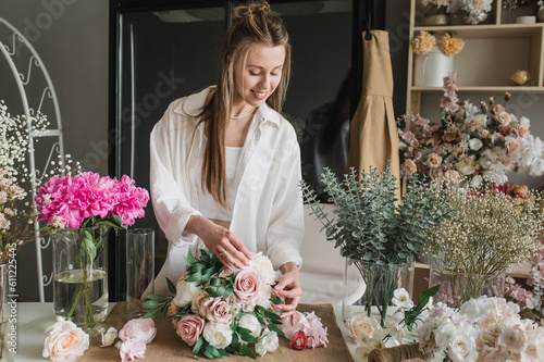 A woman florist is working hard in a flower shop. Floral design studio, making decorations and arrangements. Flower delivery, order creation. Small business.