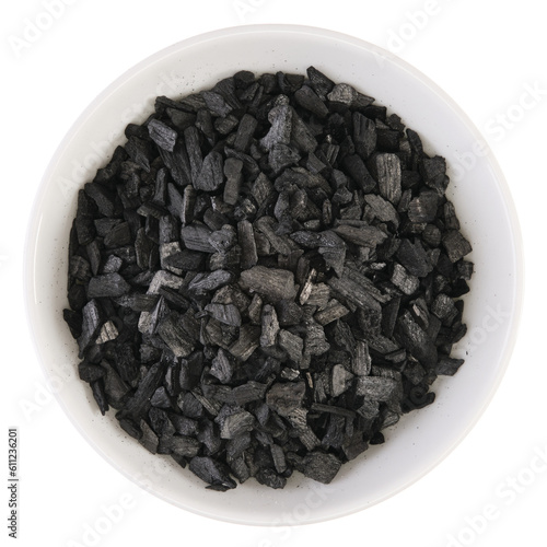 Overhead view of charcoal soaked with styrax balm (benzoin resin) in a white bowl, isolated on background
