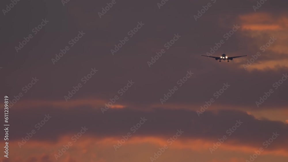 Airplane flies to land in a fiery sunset, cinematic footage. Beautiful cloudy sunset. Airplane in the sky, background Airplane flies to land in a fiery sunset, cinematic footage. Beautiful cloudy sunset. Airplane in the sky, background