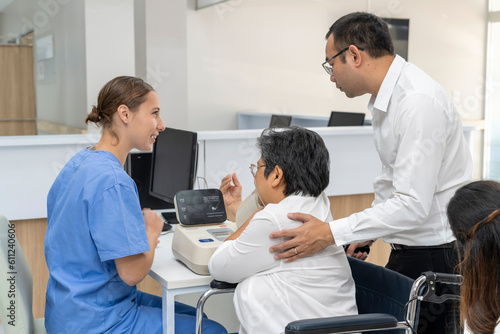 Young nurse use Automatic Blood Pressure Monitor for an aged woman