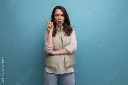 positive young brunette lady showing inspiration with hand on studio background with copy space