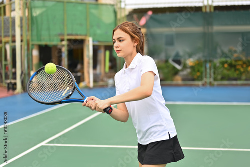 Shot of young sporty woman tennis player hitting ball with a racket during match. Fitness, sport, exercise concept