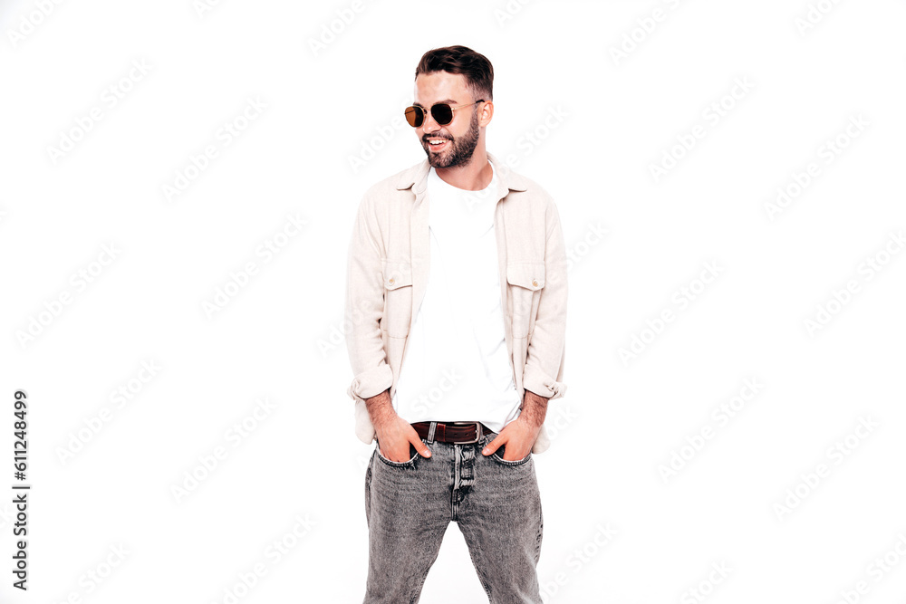 Portrait of handsome smiling stylish hipster lambersexual model. Sexy man dressed in white T-shirt and jeans. Fashion male isolated on white background in studio. In sunglasses Portrait of handsome smiling stylish hipster lambersexual model. Sexy man dressed in white T-shirt and jeans. Fashion male isolated on white background in studio. In sunglasses