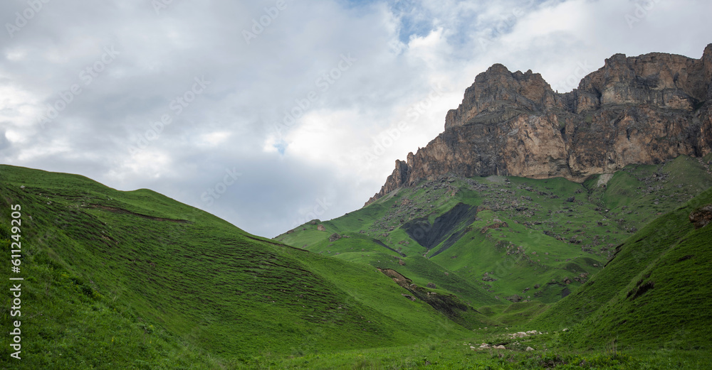 Summer mountain landscape. Amazing view of the valley and lush green pastures in the Caucasus, Georgia. Valley surrounded by high mountain ranges. Cloudy and rainy day in spring, low storm clouds.