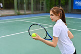 Image of pretty young female tennis player with racket serving ball during match