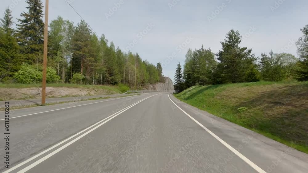 The car travels along the road and eventually drives under a stone bridge, continuing its journey through the scenic route. The car travels along the road and eventually drives under a stone bridge, continuing its journey through the scenic route.