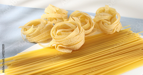 Raw Italian pasta fettuccine  spaghetti  fusilli  penne. traditional italian food close up. types of uncooked pasta on a white background. egg noodles. mediterranean cuisine.
