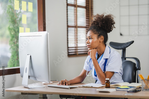 African american female doctor sitting in front of computer at her clinic office