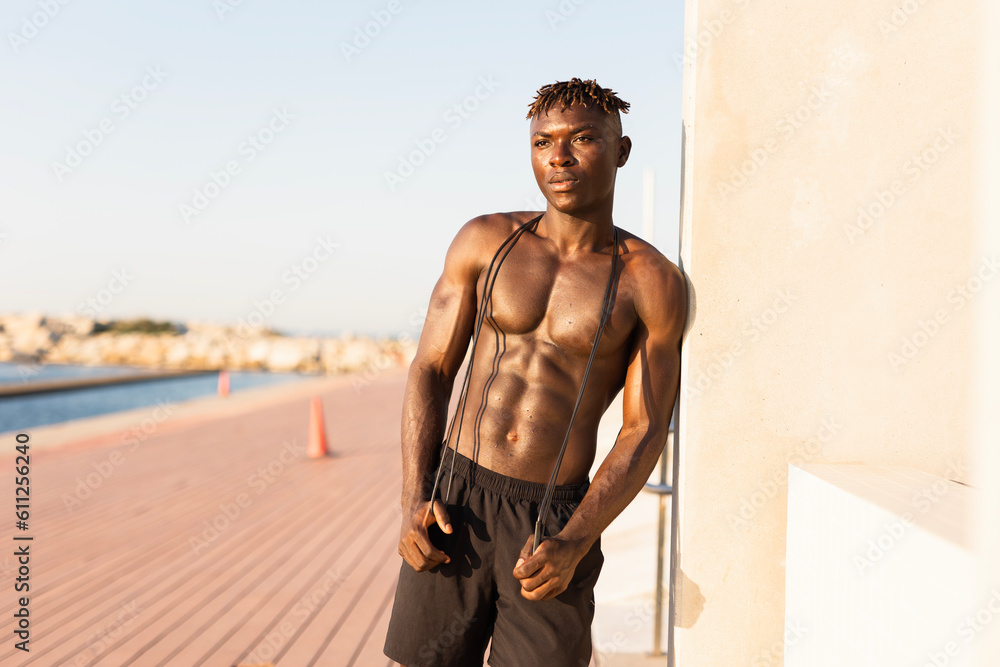 Obraz premium Fitness training outdoors. Handsome African man resting after training outside..