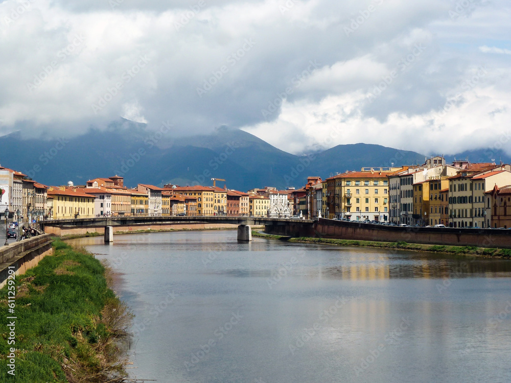 The bridge over the river in the ancient city on the background of the mountains in the clouds
