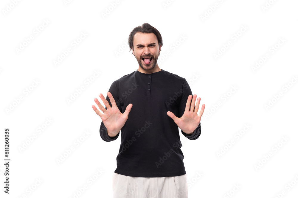 Fototapeta premium young confused handsome brunet european man in black sweatshirt on isolated white background