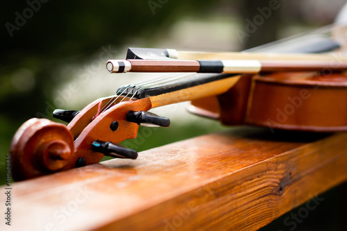 Violin and bow lie on a wide wooden railing