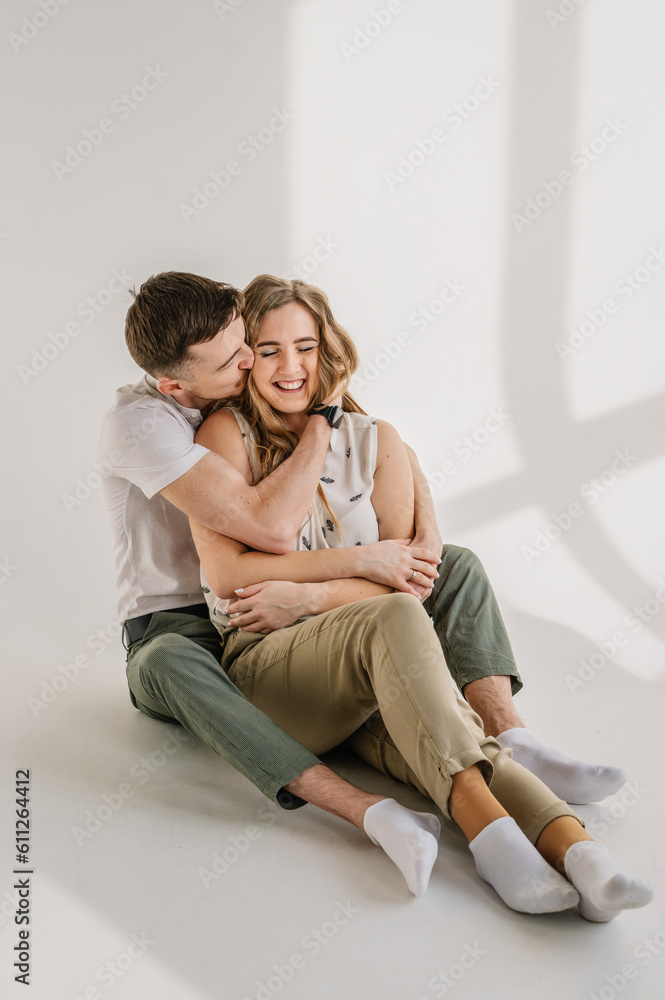 Family moving into new house, feeling joy. Couple in love. Young happy man and woman isolated on white background studio. Funny couple sit, hug and relax on floor on wall at home. Relocation concept.