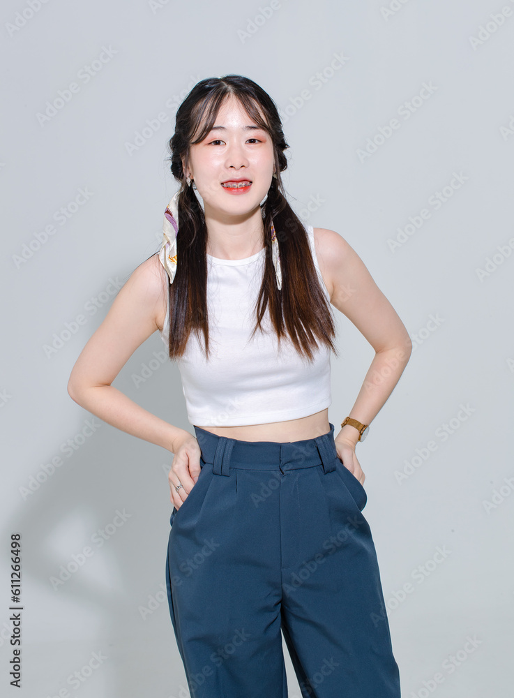Portrait isolated cutout studio shot of Asian young pretty female fashion model with pigtails braids hairstyle in fashionable sleeveless crop top shirt cargo pants standing posing on white background Portrait isolated cutout studio shot of Asian young pretty female fashion model with pigtails braids hairstyle in fashionable sleeveless crop top shirt cargo pants standing posing on white background