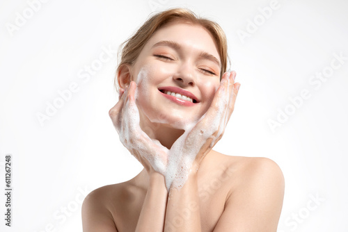 Behang A happy young woman cleanses her skin with a gentle facial foam, the model applies the cleanser to her skin and smiles