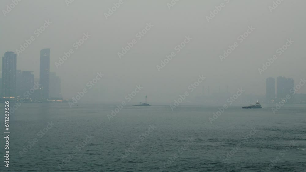 New York City covered in smoke from wildfires seen from across the east river with tug boat in the distance. slow motion 40fps. New York City covered in smoke from wildfires seen from across the east river with tug boat in the distance. slow motion 40fps.