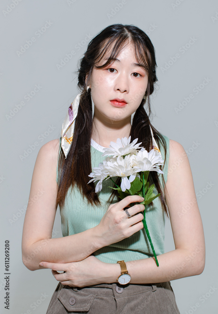 Portrait isolated cutout closeup studio shot of Asian young sad female teenage fashion model with pigtails hairstyle in casual trendy shirt standing posing holding flowers bouquet on white background Portrait isolated cutout closeup studio shot of Asian young sad female teenage fashion model with pigtails hairstyle in casual trendy shirt standing posing holding flowers bouquet on white background