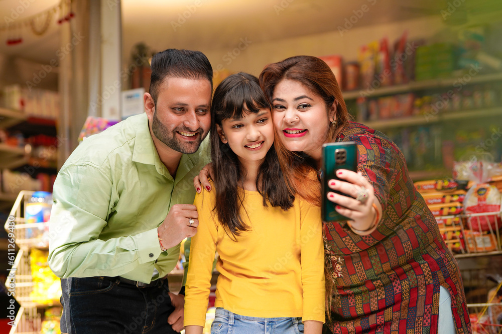 Obraz premium Indian family taking selfie in smartphone at grocery shop.