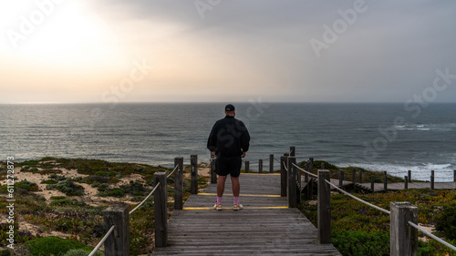 Man tourist early spring on wooden walkway to beautiful sand beach sea view near Pataias, Portugal. photo