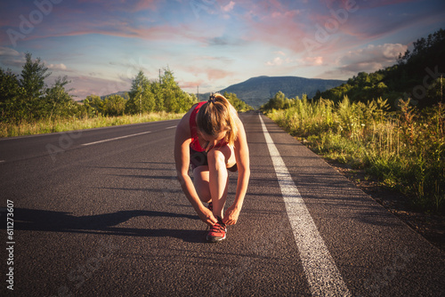 Fitness blonde woman running on the asphalt road at the mountains