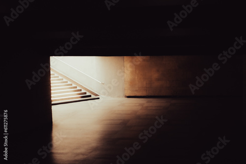 Melancholic urban background of an empty underground pedestrian crossing and a bright light at the end of the tunnel. Concepts of life, death, afterlife, society and modern architecture.