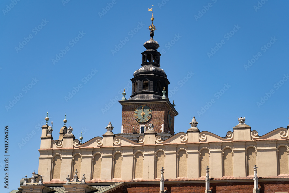 Fototapeta premium Main Square Market in Krakow, Poland. Town Hall Tower or Wieża Ratuszowa Kraków and the Cloth Hall Sukiennice, in the Old Town district of Cracow.