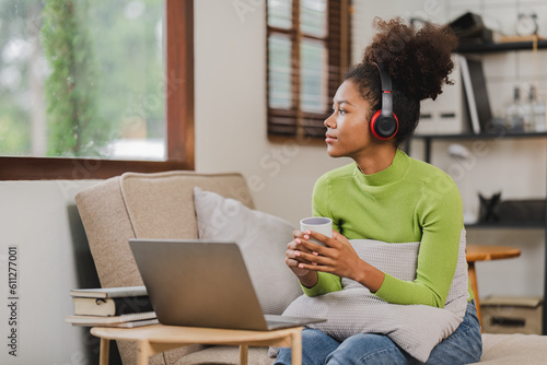 African american woman sitting on sofa listening to relaxing music social play at home