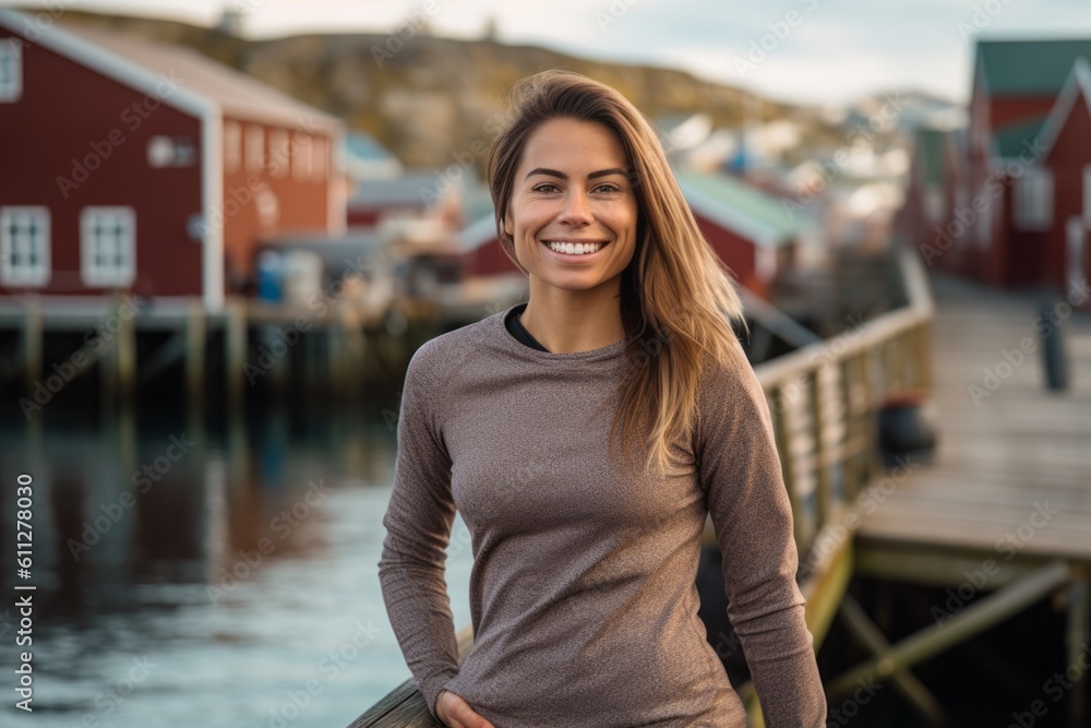 Lifestyle portrait photography of a grinning girl in her 30s wearing a versatile pair of leggings against a picturesque fishing village background. With generative AI technology