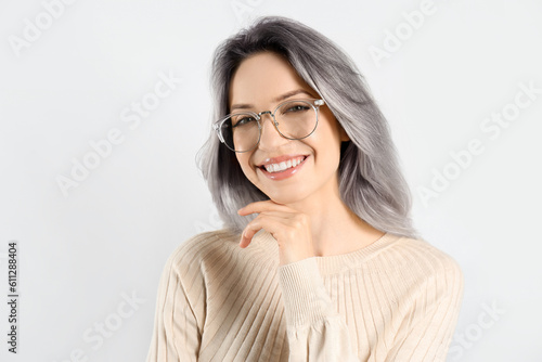 Portrait of smiling woman with ash hair color on light background