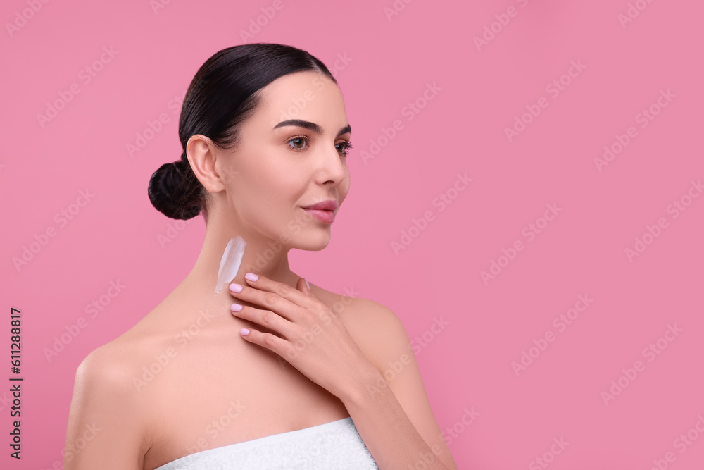 Naklejka premium Beautiful woman with smear of body cream on her neck against pink background, space for text