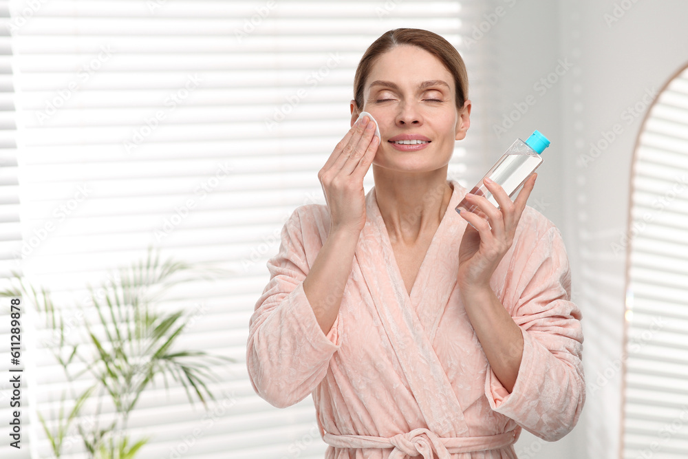 Beautiful woman removing makeup with cotton pad indoors Beautiful woman removing makeup with cotton pad indoors