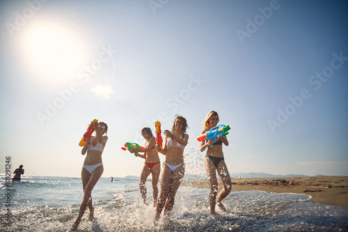 Friends having fun on the beach.Playful girl have fun with water gun at beach at sunny day.