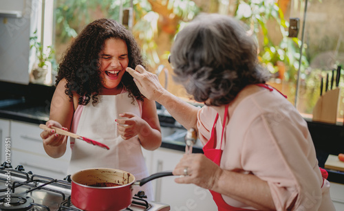 Avó e neta Brasilieiras brincando na cozinha enquanto preparam uma sobremesa para o dia das mães photo