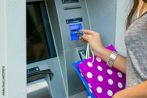 Woman with shopping bags withdrawing the money.