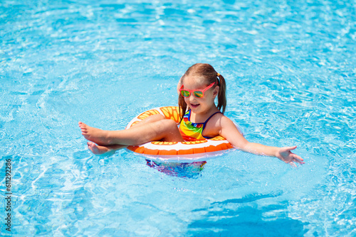 Child in swimming pool on toy ring. Kids swim.