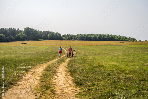Back view of the caucasian woman and her father going near the forest together