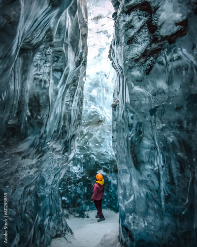 Exploring woman observes nature inside an ice cave photo
