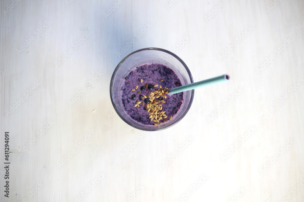 Smoothie glass with blueberry, linen seeds, milk on white background