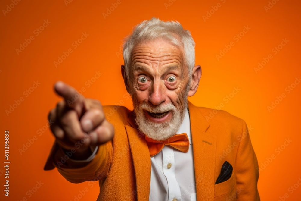 Medium shot portrait photography of a glad old man making a i see you gesture pointing at one's eyes against a bright orange background. With generative AI technology