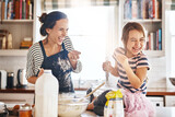 Mother, play or kid baking in kitchen as a happy family with an excited girl laughing or learning cookies recipe. Playful, flour or funny mom helping or teaching kid to bake for development at home