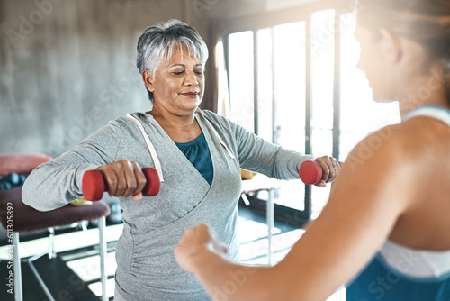 Coaching, dumbbell and fitness with old woman and personal trainer for support, health or physiotherapy. Training, weightlifting and workout with senior client and female trainer for elderly exercise
