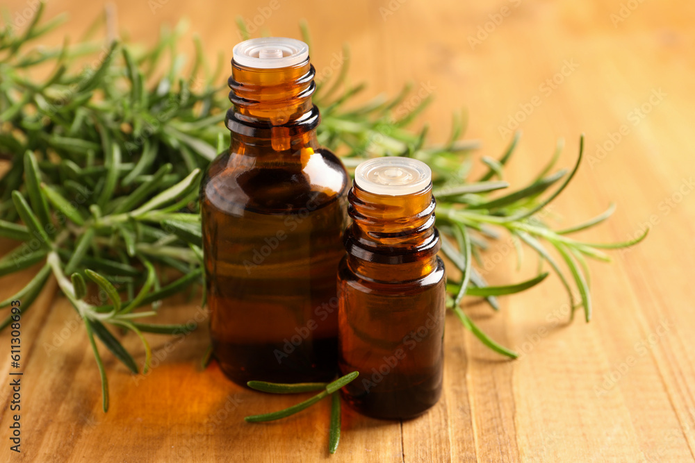 Bottles of rosemary oil and fresh twigs on wooden table, closeup Bottles of rosemary oil and fresh twigs on wooden table, closeup