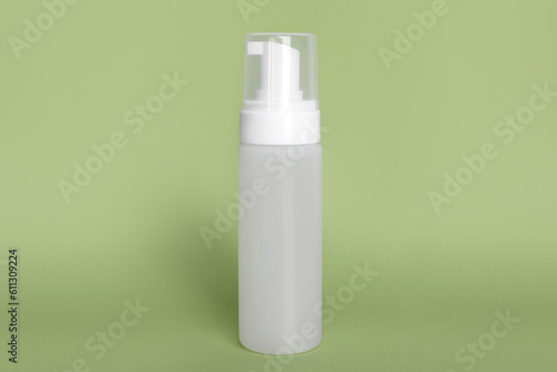 Bottle of face cleansing product on olive background. Space for text