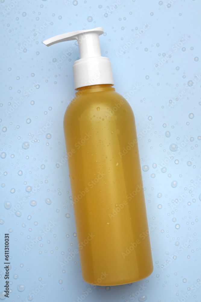 Wet bottle of face cleansing product on light blue background, top view Wet bottle of face cleansing product on light blue background, top view